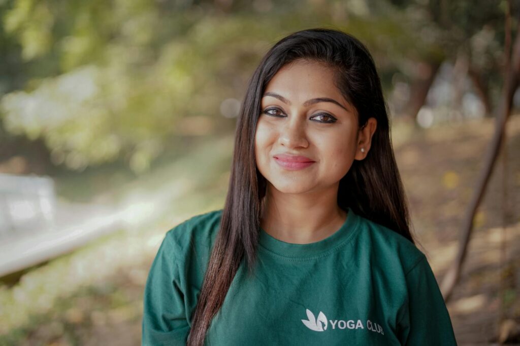 A smiling woman in a green shirt enjoying a sunny day outdoors.